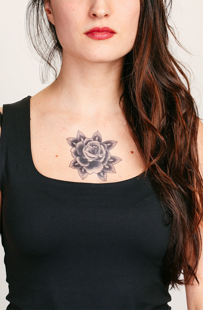 Black rose tattoo on a person's upper chest