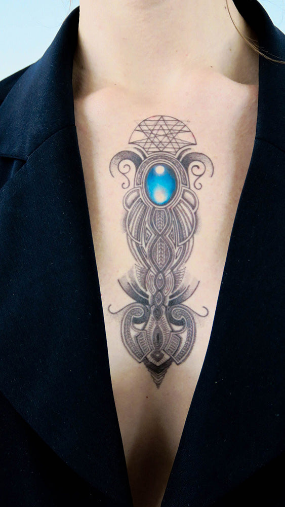 Blue stone geometric tattoo with geometric design on a person’s upper chest