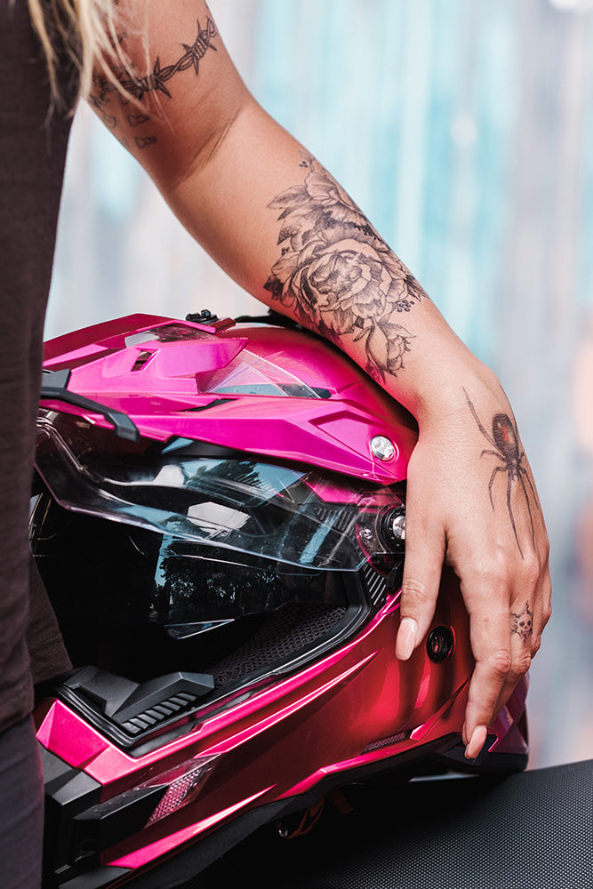 Flower ornament tattoo on a person’s arm holding a helmet