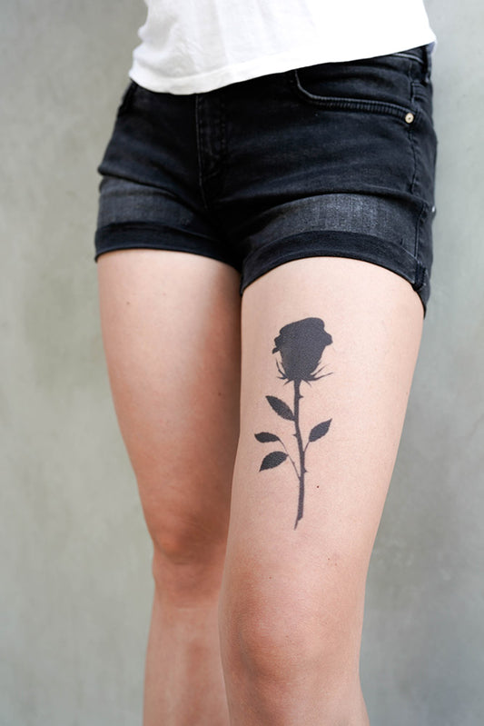 Rose silhouette tattoo on a person's left thigh