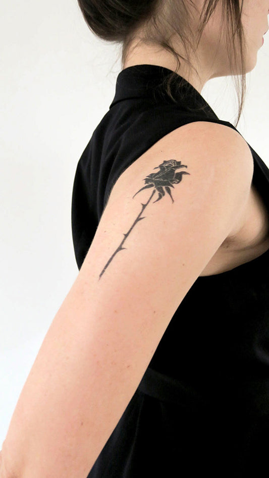 Rose silhouette tattoo on a person's upper arm