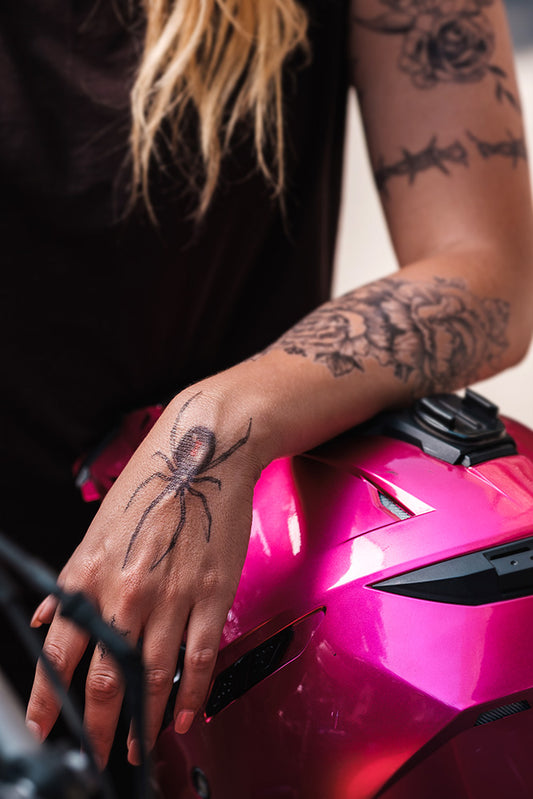 Realistic black widow tattoo on a person's hand