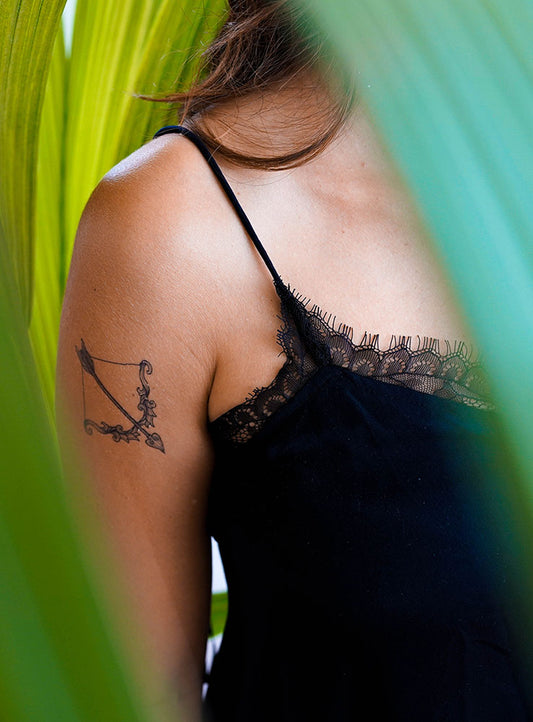 Upper arm with a realistic temporary tattoo of a bow and arrow
