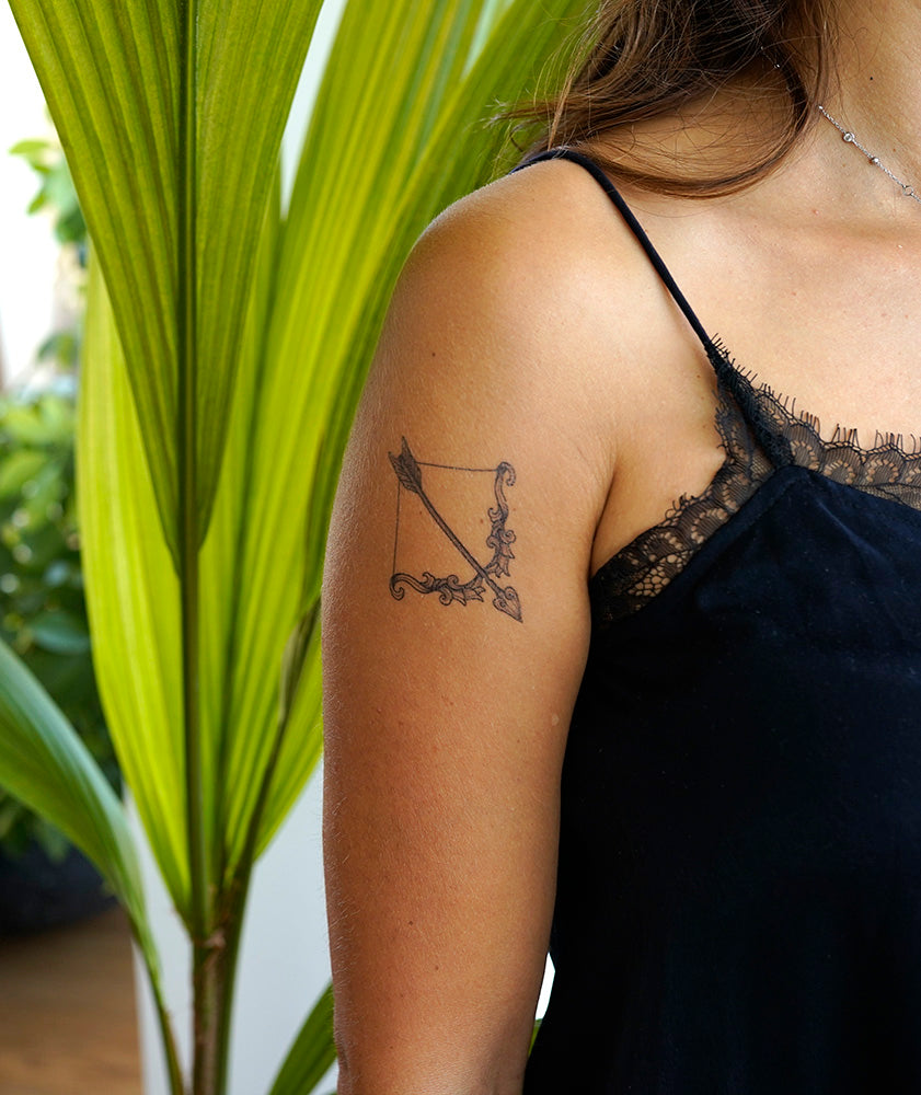 Upper arm with a realistic temporary tattoo of a bow and arrow